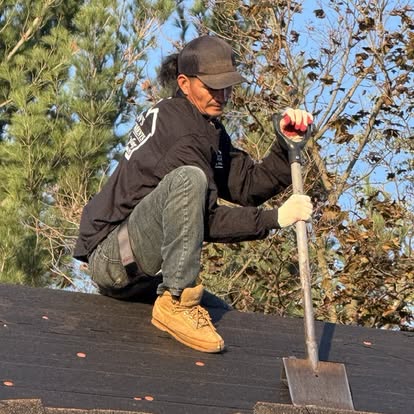 Thompson Home Improvements roofer kneeling with a tear-off shovel on a stripped roof during a full replacement