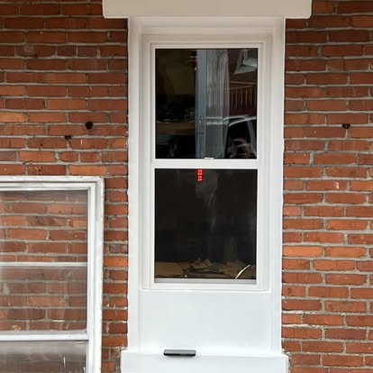 New white double-hung replacement window with clean white trim in the same brick opening in York, Pennsylvania