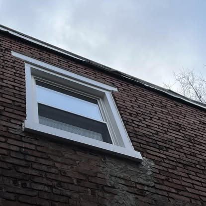 New white double-hung window with fresh white trim installed in a brick gable end in York, Pennsylvania