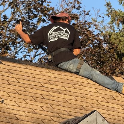 Roofer straddling a roof ridge installing cap shingles at golden hour in Hanover, Pennsylvania